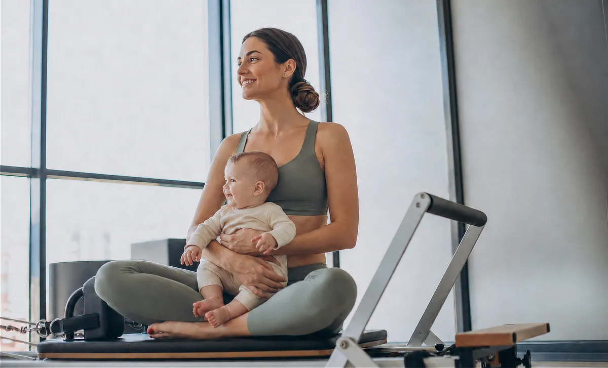 pilates-reformer-postnatal-pilates10 Madre con su bebé sentada durante una clase de Pilates Reformer Postnatal